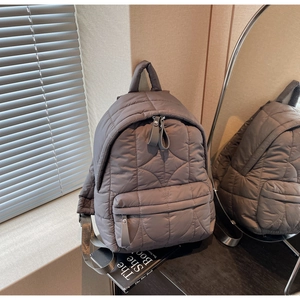 Macro view of grey star-quilted puffer backpack featuring high-quality nylon texture