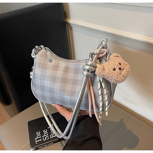 Detail view of silver checkered hobo bag with teddy bear charm and knotted shoulder strap