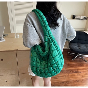 Detail of a bright green quilted puffer shoulder bag with soft textured padding