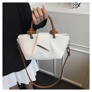 Detail of white lychee pattern leather tote bag with brown knotted handle and asymmetrical flap