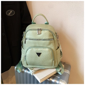 Detailed close-up of light green pebbled leather backpack on silver suitcase