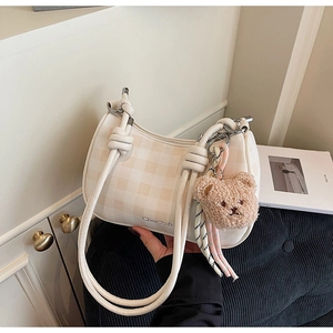 Detail view of checkered hobo bag with thick shoulder strap and cute bear pendant