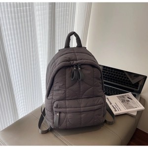 Detailed view of the grey quilted backpack showing wave patterns and puffer texture material