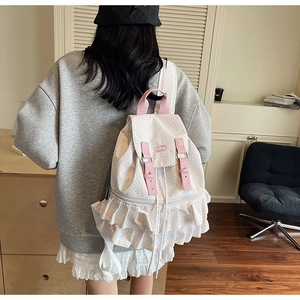 Detail of canvas backpack featuring pink polka dots and elegant ruffled skirt trim design