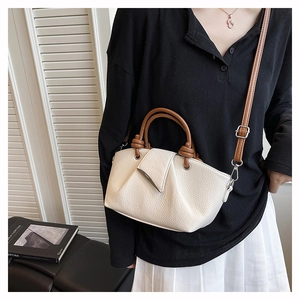 Close-up of a retro pleated bucket bag in off-white leather with brown knotted handles