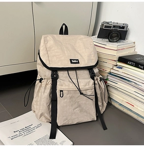 Detail of beige outdoor backpack with black strap buckles and branded DAPJ square label