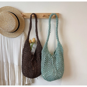 Close-up of hand-woven hollow knit tote bags in dark brown and light green for summer