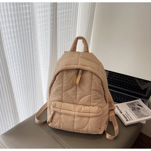 Detailed view of camel quilted puffer backpack with wave stitching and soft padded texture