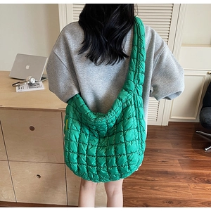 Green quilted puffer bag with wide strap worn over shoulder for a casual commute look
