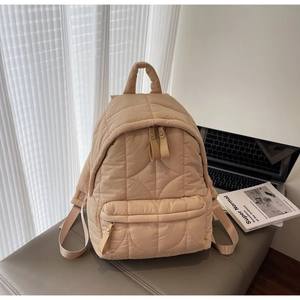 Detail of beige quilted backpack with wavy stitching and premium leather pull tabs