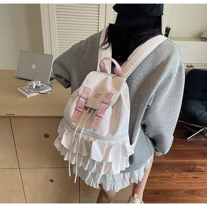 Detailed back view of a white polka dot backpack with pink straps and ruffle hem detail