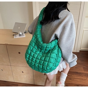 Close-up of vibrant green quilted puffy shoulder bag with diamond texture worn by a model