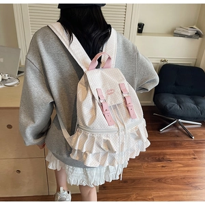 Detailed close-up of white and pink polka dot backpack with ruffled bottom design