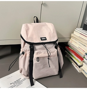 Macro view of light beige nylon backpack featuring black contrast trim and DAPJ label