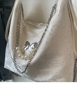 Détail du tissu jacquard blanc avec cristaux, boucle papillon et chaîne de perles