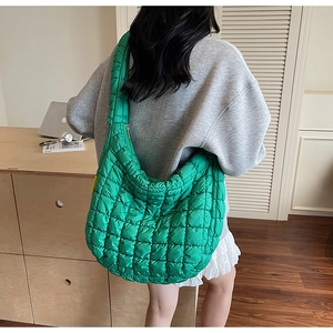 Rear view of a model wearing a green quilted cloud bag in a bright minimalist interior