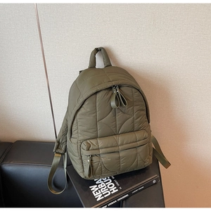 Detail of army green quilted backpack showing padded handle and zip closure