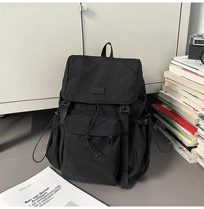 Detail of the black waterproof nylon backpack featuring flap buckle and drawstring closure