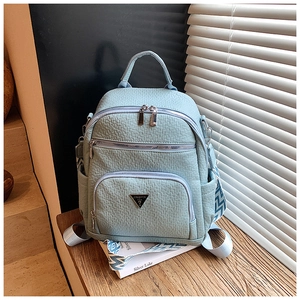 Detail of light blue backpack featuring textured grain surface and triangular metal logo