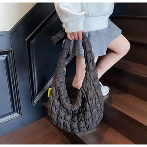 Detailed view of black quilted puff tote bag featuring a yellow fashion label on the side