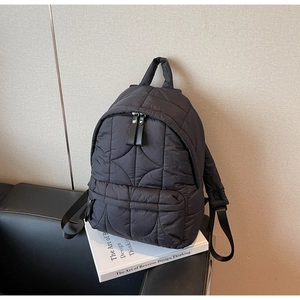 Close-up of black quilted puffer backpack featuring high-density nylon texture and zippers