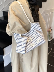 Blue and white striped canvas tote bag with letter patches and matching pouch on model