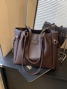 Grande borsa tote in pelle marrone scuro con anelli metallici e design minimalista