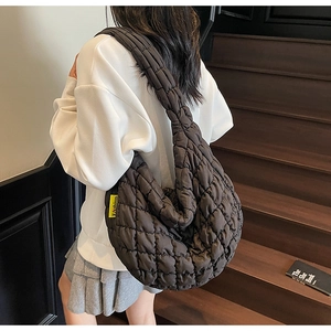Detail of dark brown quilted puffer cloud bag with glossy texture and fashion tag