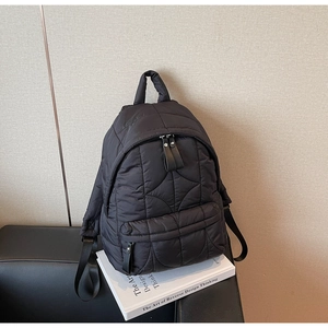 Detailed view of black quilted nylon backpack with zip pocket and padded top handle