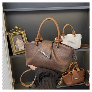Close-up of litchi texture leather handbag with knot handle and silver metal buckle