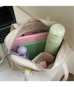 Vista dall'alto dell'ampio interno di una borsa tote in tela beige con laptop e oggetti quotidiani