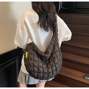 Close-up of quilted puffer bag with yellow Fashion label on a textured nylon crossbody