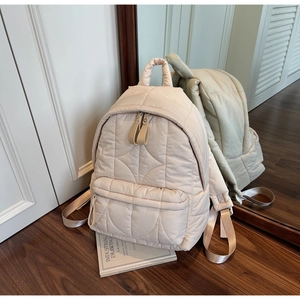 Detail of off-white quilted backpack showing soft wavy texture and sturdy top handle