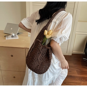 Close-up of deep brown hollow woven shoulder bag with thick strap and round structure