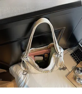 Détail d'un sac à bandoulière blanc montrant un intérieur spacieux et des objets