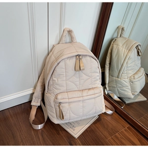 Mirror reflection showing details of beige quilted backpack with light nylon texture
