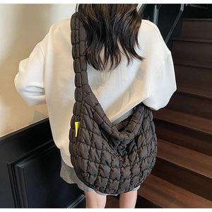 Detail of black quilted cloud bag with puffy texture and distinctive yellow woven label