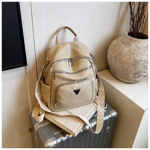 Detail of a cream faux leather backpack with jacquard strap on a travel suitcase