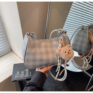 Detail of silver checkered hobo bag with metal ring handle and cute bear charm