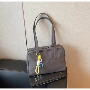 Dettaglio della borsa tote grigio scuro con ciondolo a stella e tasca frontale