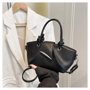 Detailed view of black lychee grain texture and unique metal buckle on the handbag