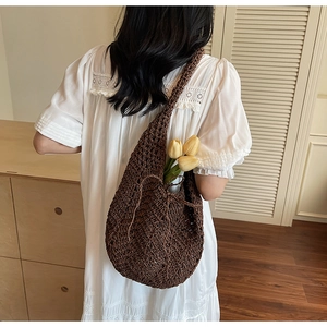 Detail view of brown hollow knit tote bag with drawstring on white lace dress