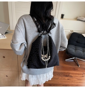 Vue détaillée du sac à dos noir avec chaînes argentées, perles et papillons