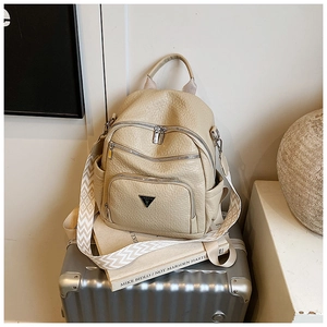 Detail of light beige textured leather backpack with multiple zippers and wide woven strap
