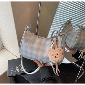 Detail of silver checkered hobo bag with plush bear charm and woven shoulder strap