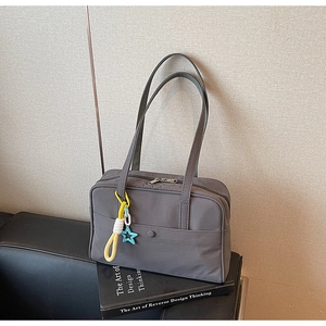 Dettaglio della borsa tote in nylon grigio scuro con ciondolo a stella su sedia