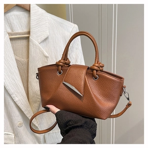 Detail of brown lychee leather tote bag with silver crescent buckle and knotted handle