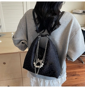 Détail du sac à dos noir avec chaînes argentées, perles blanches et motifs papillons