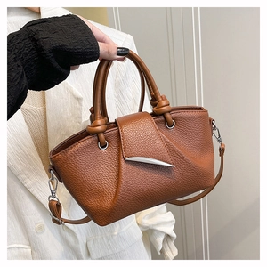 Detail of brown litchi pattern leather handbag with silver crescent buckle and knot handle