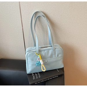 Dettaglio della borsa tote in tela azzurra con ciondolo a stella appoggiata su un libro